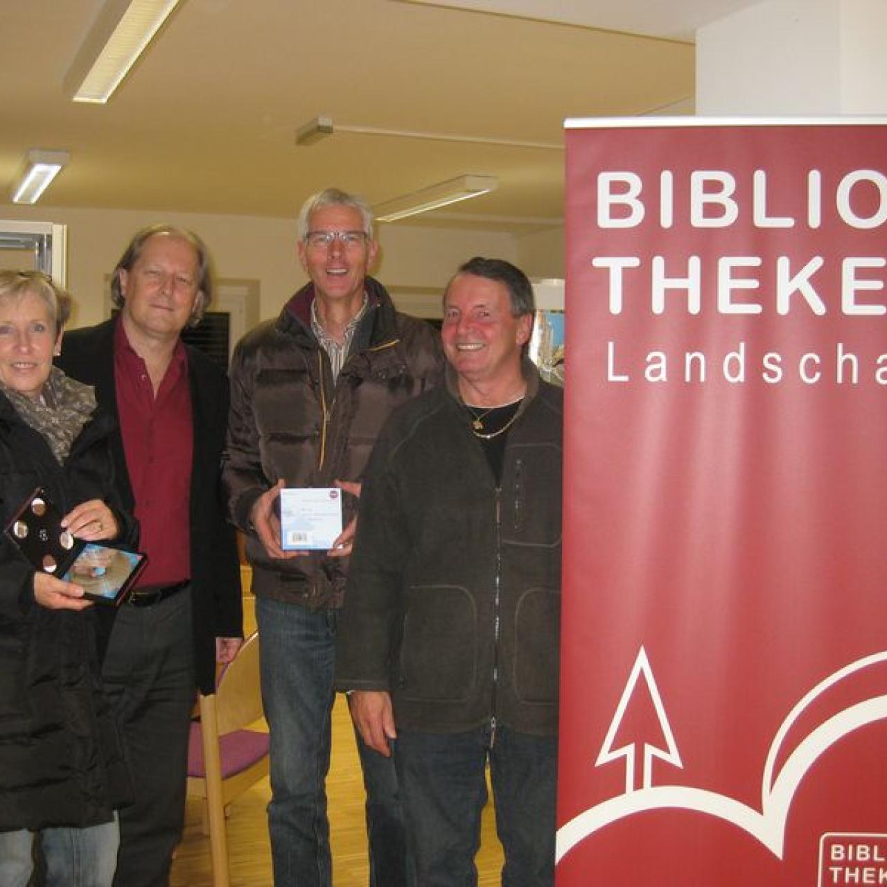 Vier Personen links neben dem Rollup mit Aufdruck "Bibliotheken Landschaft"